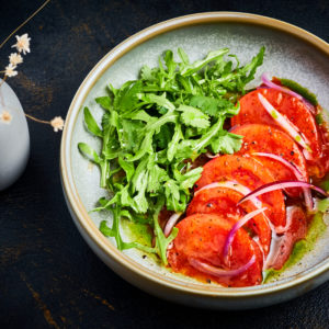 Салат с томатами, рукколой, красным луком и зеленым маслом